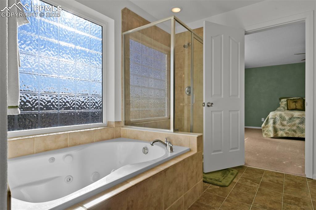 Image 24 of 50: Bathroom featuring a bath, two vanities, a stall shower, and recessed light