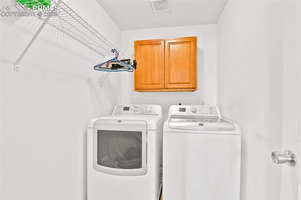 Image 32 of 50: Laundry area featuring cabinet space and washing machine and clothes dryer