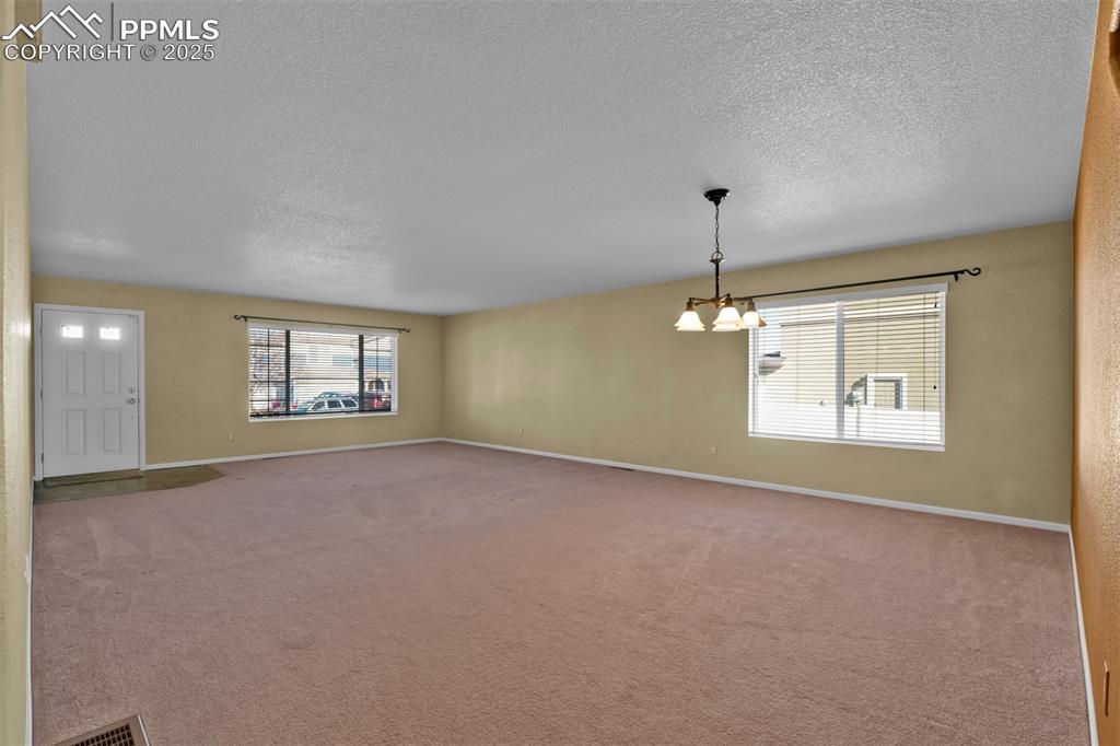 Image 6 of 50: Carpeted empty room featuring a textured ceiling and a chandelier