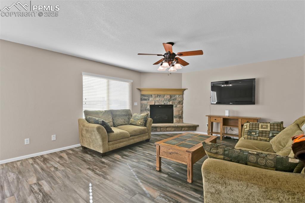 Image 9 of 50: Living area with a stone fireplace, wood finished floors