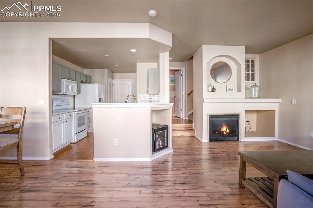 Image 4 of 26: Kitchen and access to 1/2 bath and living room area with fireplace