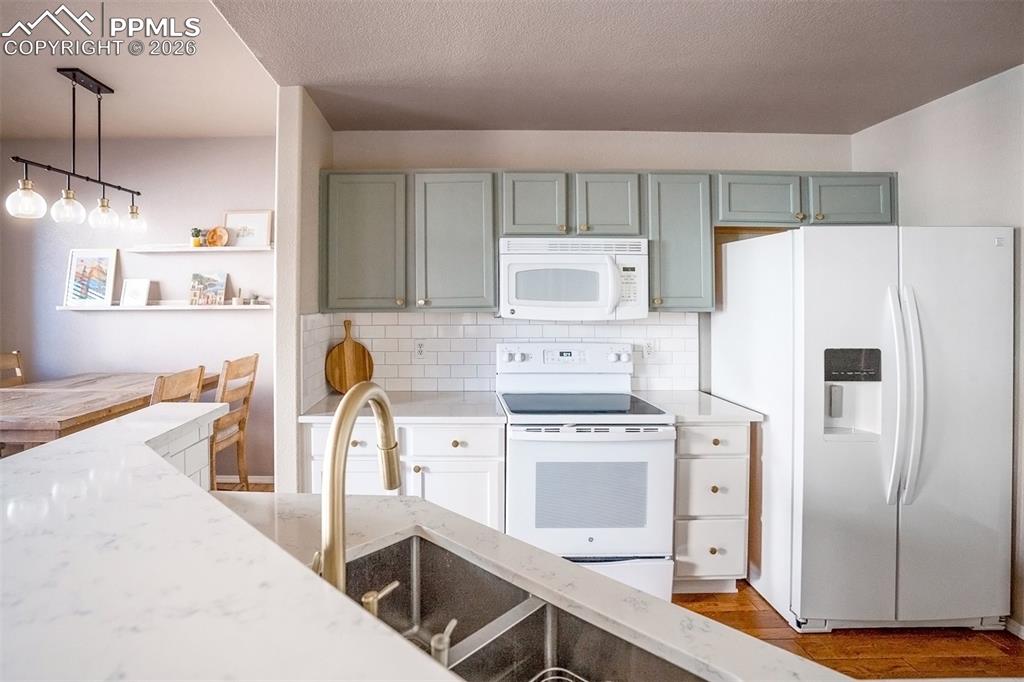Image 5 of 26: Sage green upper cabinets with white lower cabinets, quartz countertops, wh