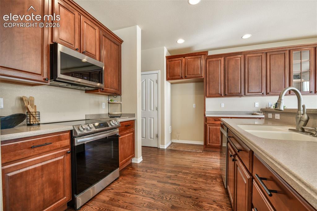 Image 11 of 50: Kitchen featuring wood-finish flooring, rich wood cabinetry, light-toned co