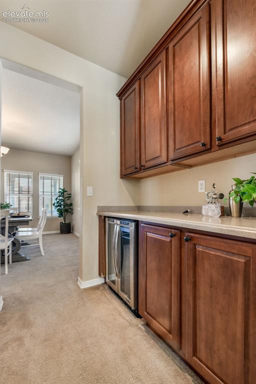 Image 16 of 50: Built-in cabinetry with a beverage cooler, stone-finish countertop, and car