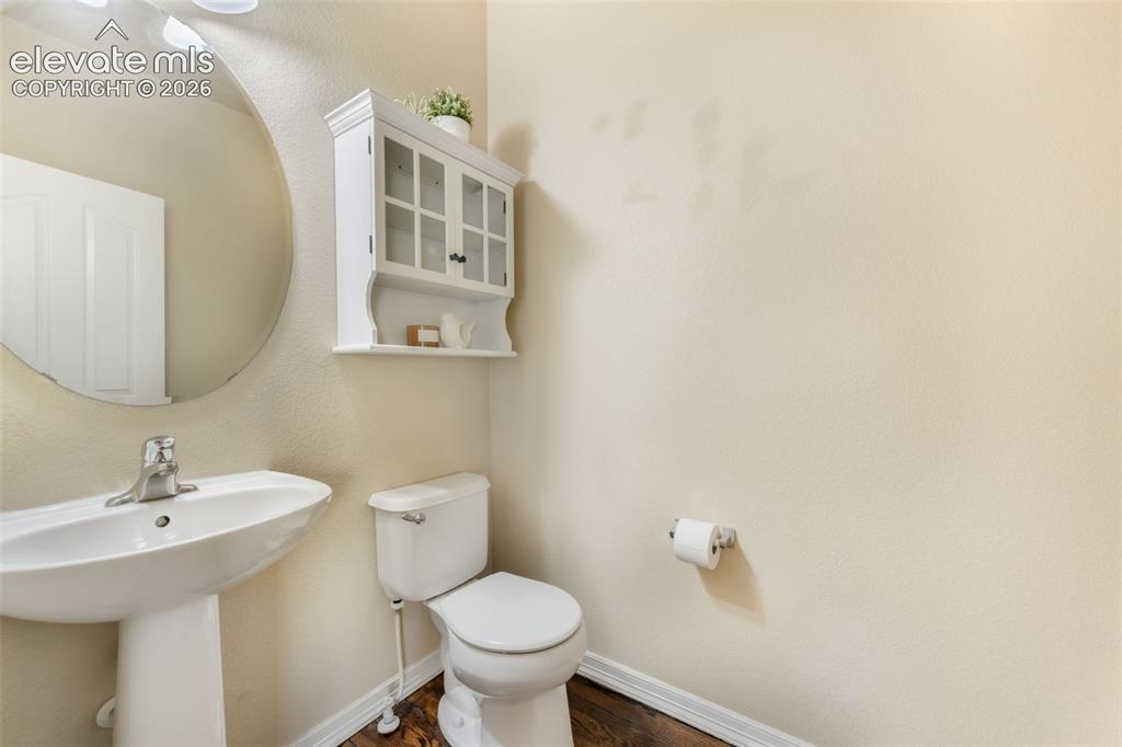 Image 17 of 50: Pedestal sink with chrome faucet, circular mirror, wall-mounted storage cab