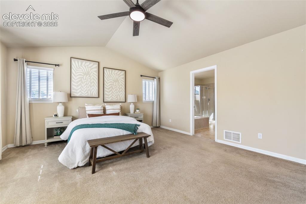 Image 20 of 50: Vaulted ceiling with an attached ceiling fan, dual windows with blinds, and