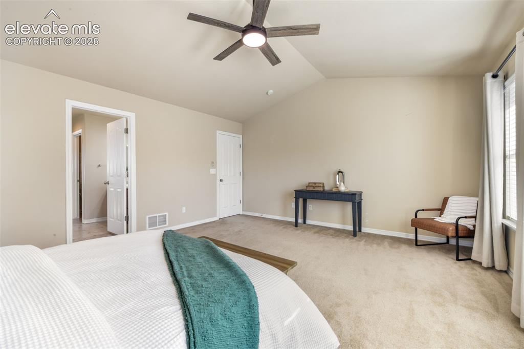 Image 21 of 50: Vaulted ceiling with an attached ceiling fan, neutral carpet flooring, and