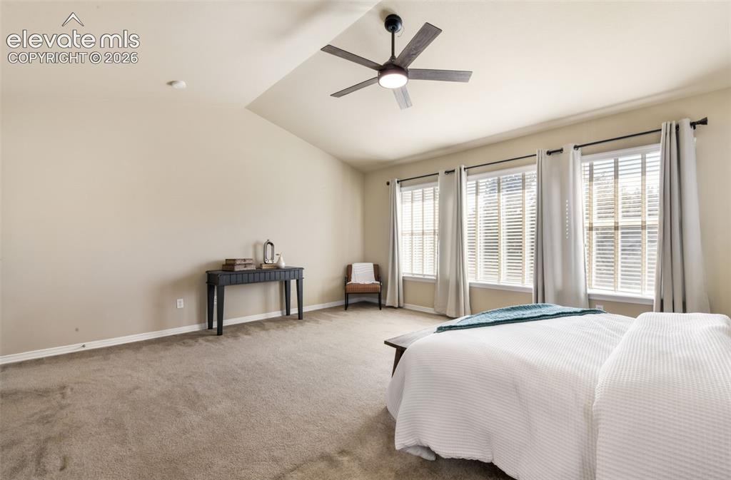 Image 22 of 50: Vaulted ceiling with an attached ceiling fan, three large windows with blin