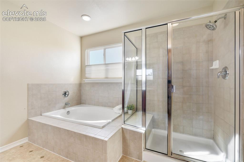 Image 24 of 50: Built-in soaking tub with tile surround, separate glass-enclosed shower wit