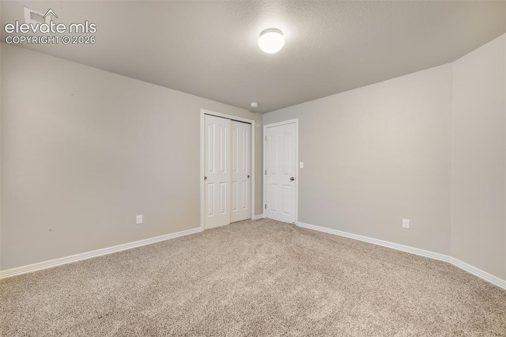 Image 42 of 50: Neutral wall paint, plush carpeting, white trim, bi-fold closet doors, and