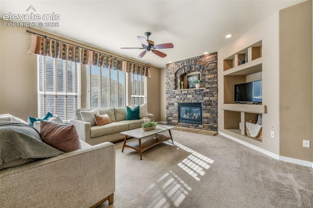 Image 8 of 50: Stone-faced fireplace with hearth, built-in shelving, recessed lighting, ce