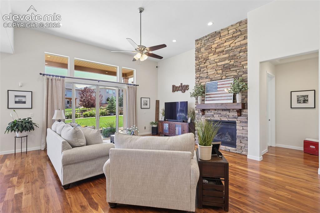 Image 10 of 50: Vaulted ceiling with a ceiling fan, stone-clad fireplace, wood mantel, glas
