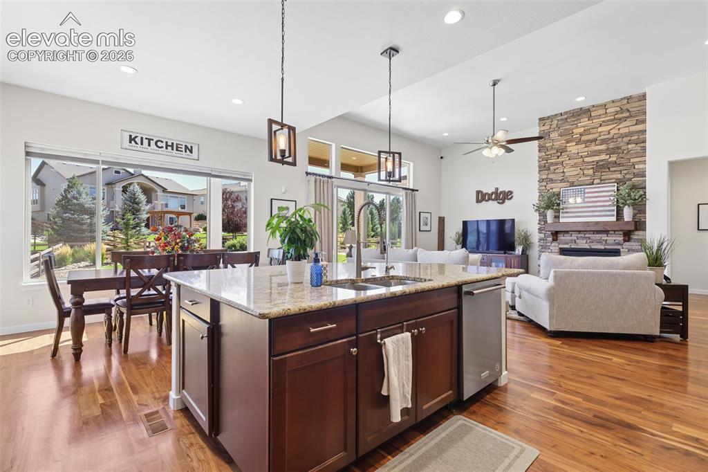 Image 15 of 50: Open-concept interior with wood-finish flooring, a kitchen island with ston