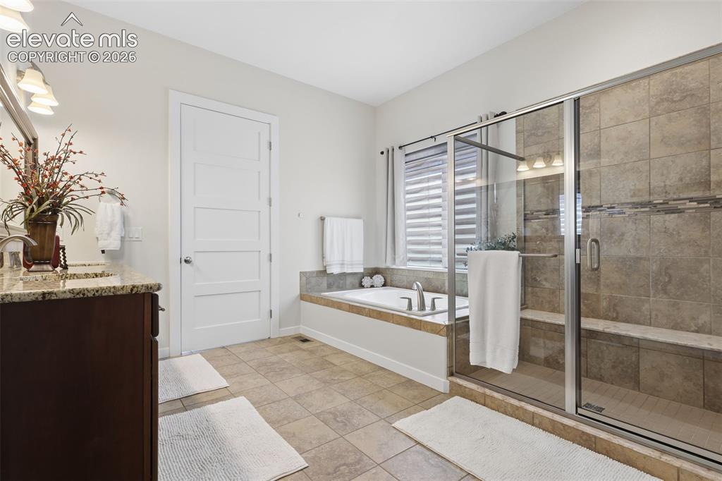 Image 23 of 50: Dual sink vanity with granite countertop, built-in soaking tub, tiled walk-