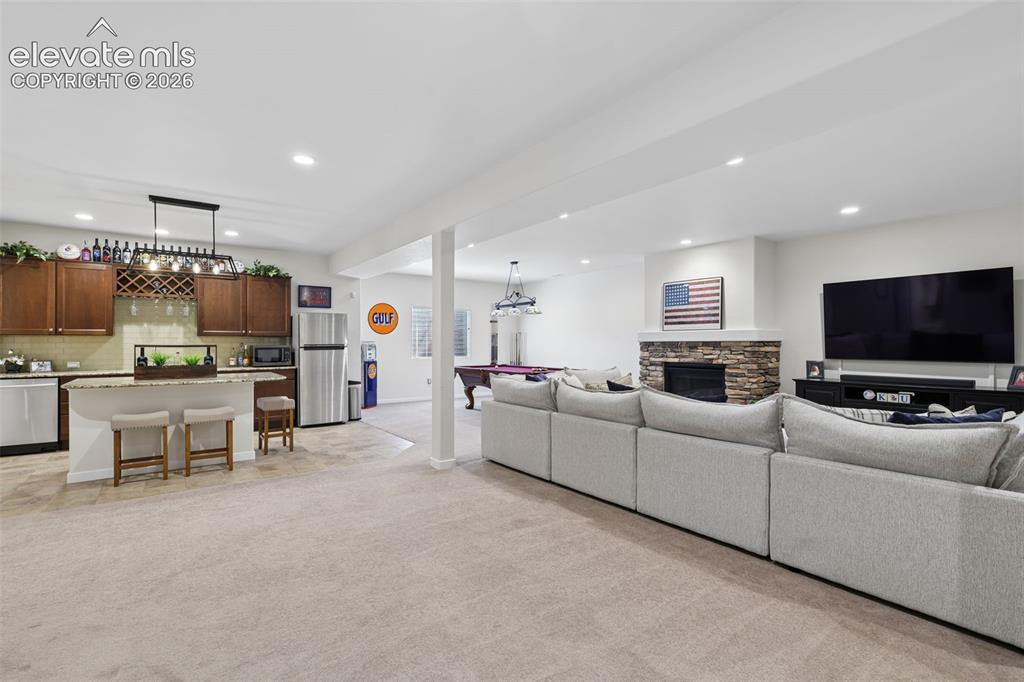 Image 33 of 50: Open-concept finished lower level featuring a full-height stone fireplace, 