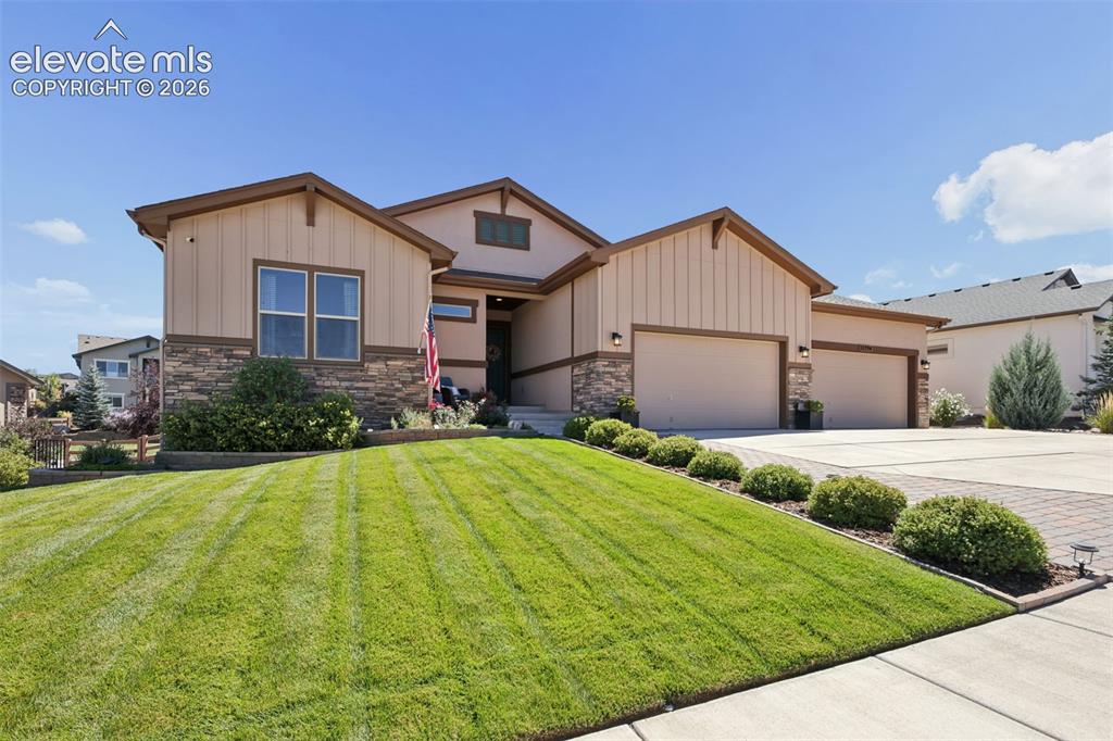 Image 4 of 50: Stone façade detailing, multi-car garage, mature landscaping, paved drivewa