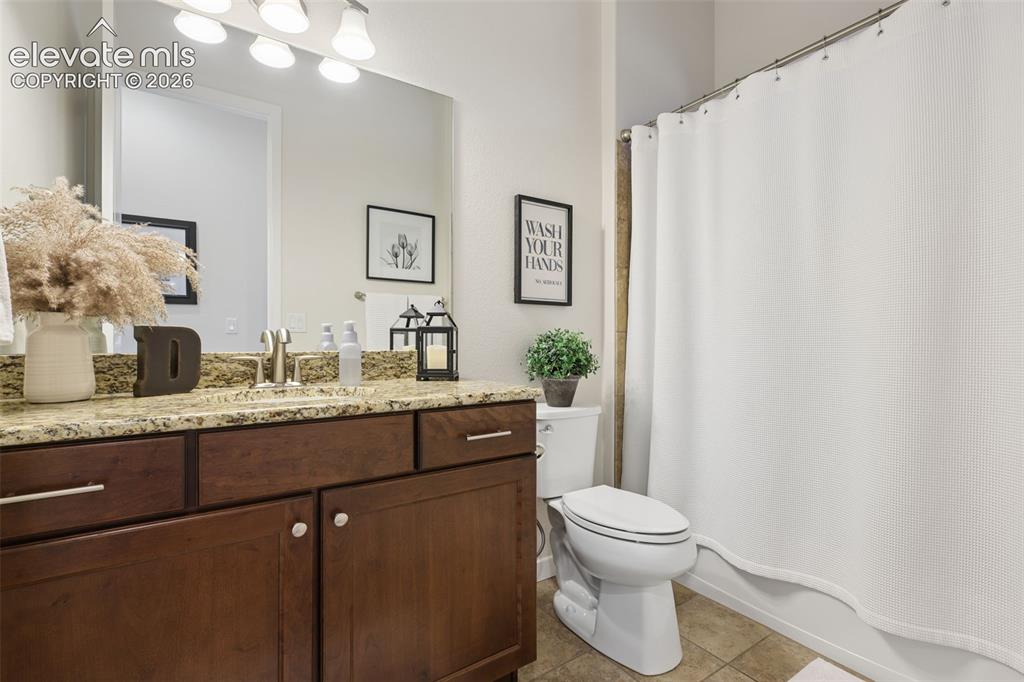 Image 44 of 50: Vanity with a granite-style countertop, undermount sink, and wood-finish ca