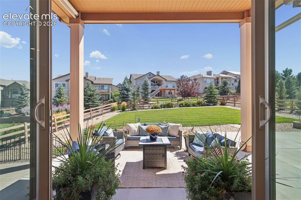 Image 45 of 50: Expansive covered patio with a textured ceiling, opening to a large, irriga