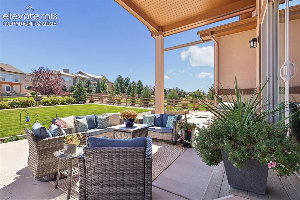 Image 46 of 50: Covered patio with an expansive manicured lawn and a privacy fence