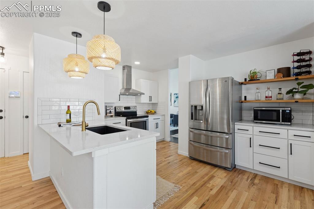 Image 12 of 36: Kitchen with stainless steel appliances, a peninsula, white cabinets, open