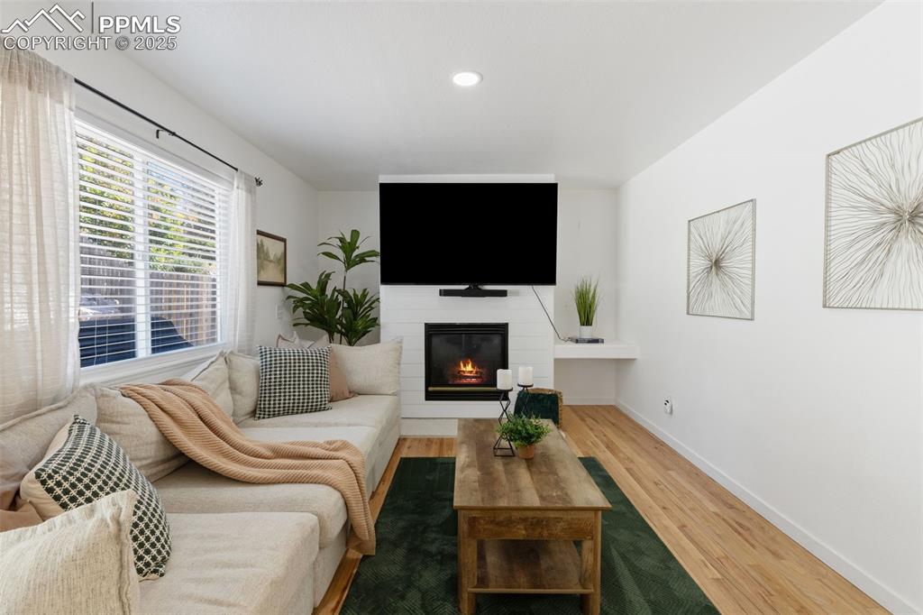 Image 15 of 36: Living room featuring wood finished floors, a glass covered fireplace, and