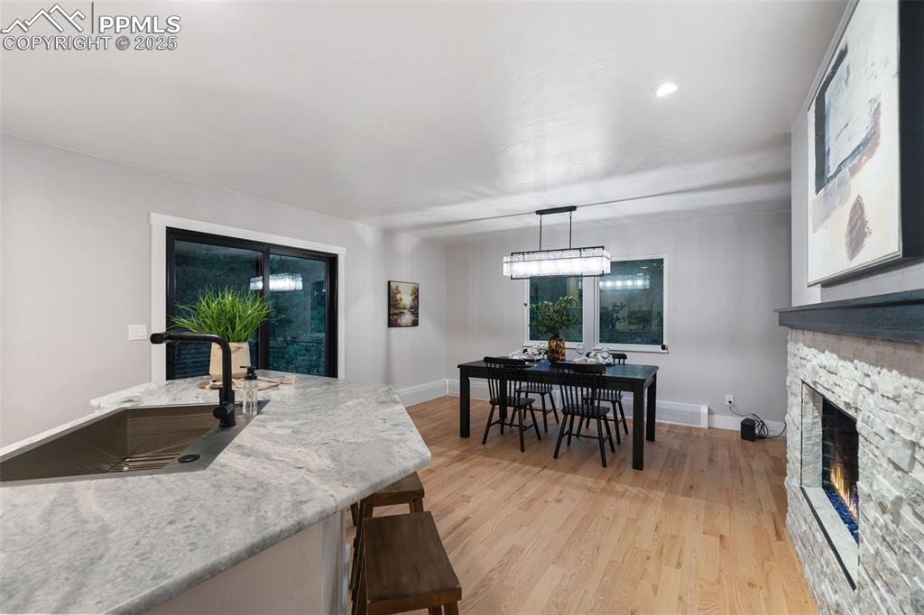 Image 10 of 48: Kitchen featuring light wood-style flooring, a stone fireplace, light stone