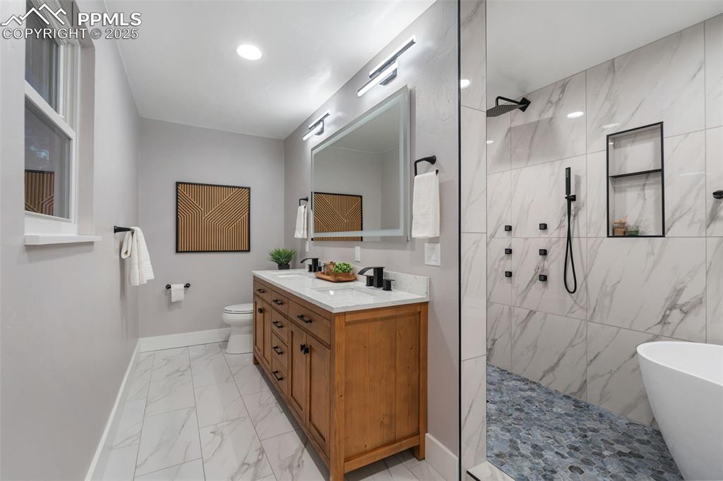 Image 20 of 48: Full bath with double vanity, a marble finish shower, a freestanding tub, a