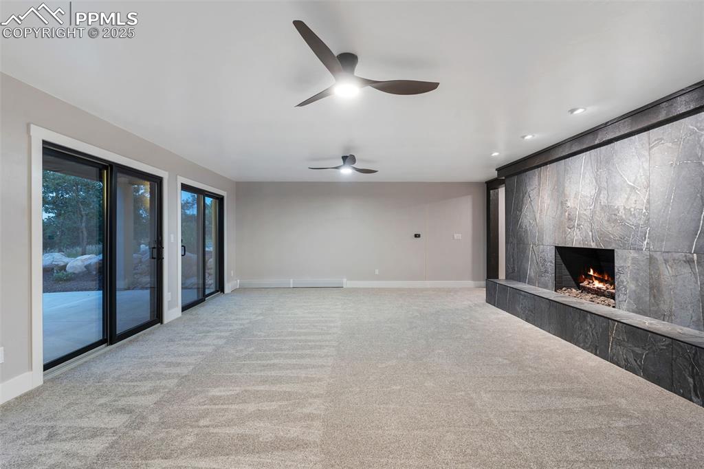 Image 25 of 48: Unfurnished living room with a fireplace, carpet flooring, and a ceiling fa