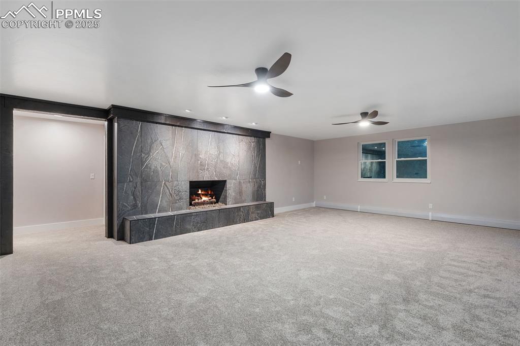 Image 26 of 48: Unfurnished living room with carpet flooring, a high end fireplace, and a c