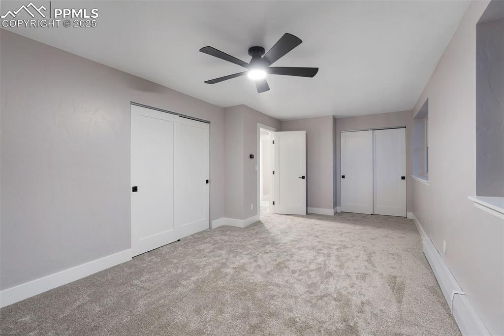 Image 29 of 48: Unfurnished bedroom with two closets, carpet floors, and ceiling fan