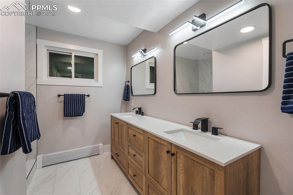 Image 32 of 48: Bathroom with marble look tile flooring, double vanity, and recessed lighti