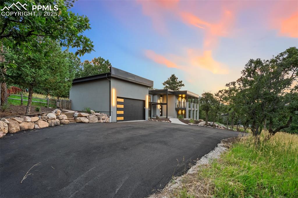 Image 34 of 48: Contemporary home featuring an attached garage, asphalt driveway, and stucc