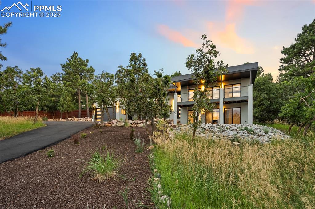Image 39 of 48: Back of house at dusk featuring asphalt driveway, a garage, and a balcony