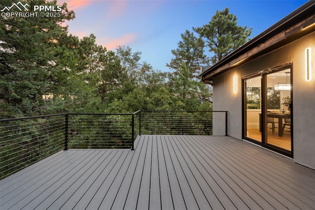 Image 44 of 48: Deck at dusk featuring view of wooded area