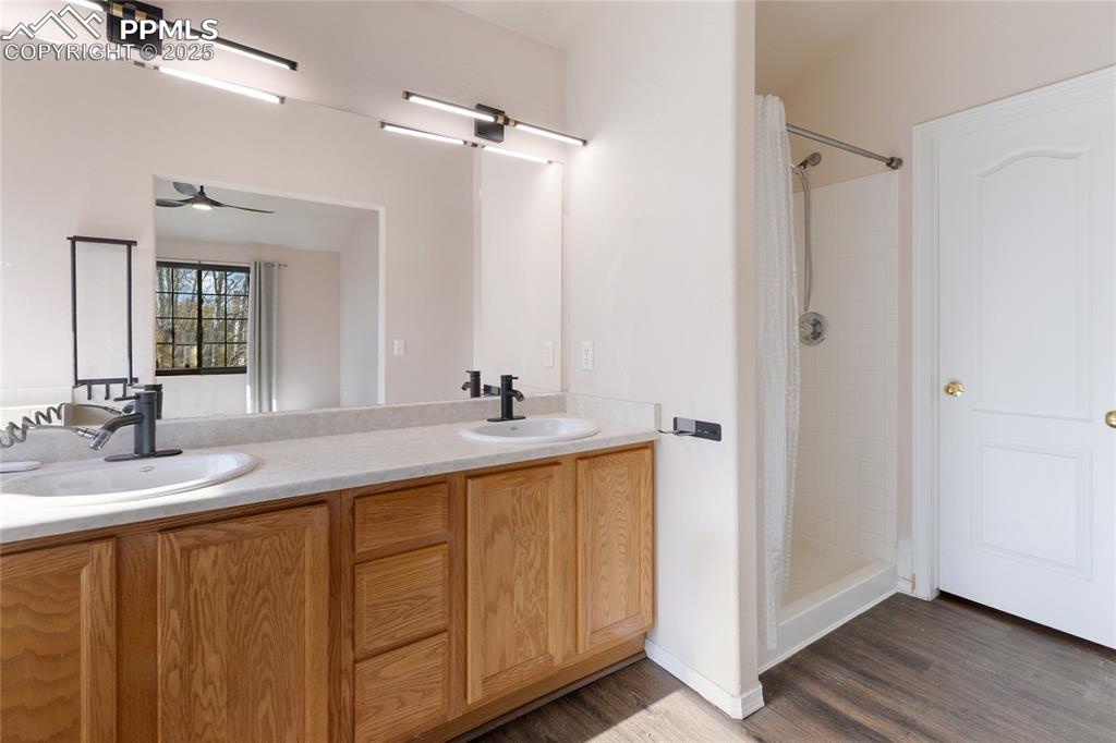 Image 15 of 37: Bathroom featuring a shower stall, double vanity, dark wood-type flooring, 