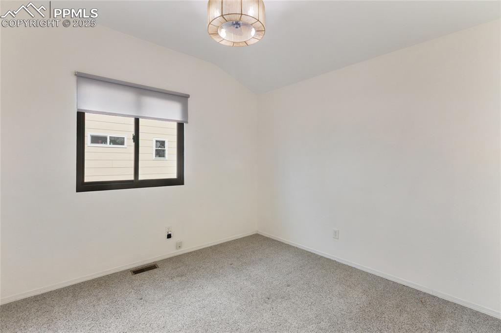 Image 21 of 37: Empty room with lofted ceiling and carpet floors