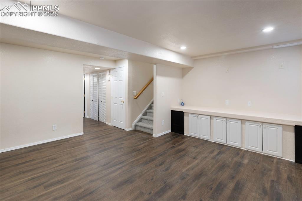 Image 28 of 37: Finished below grade area with stairs, dark wood-type flooring, and recesse