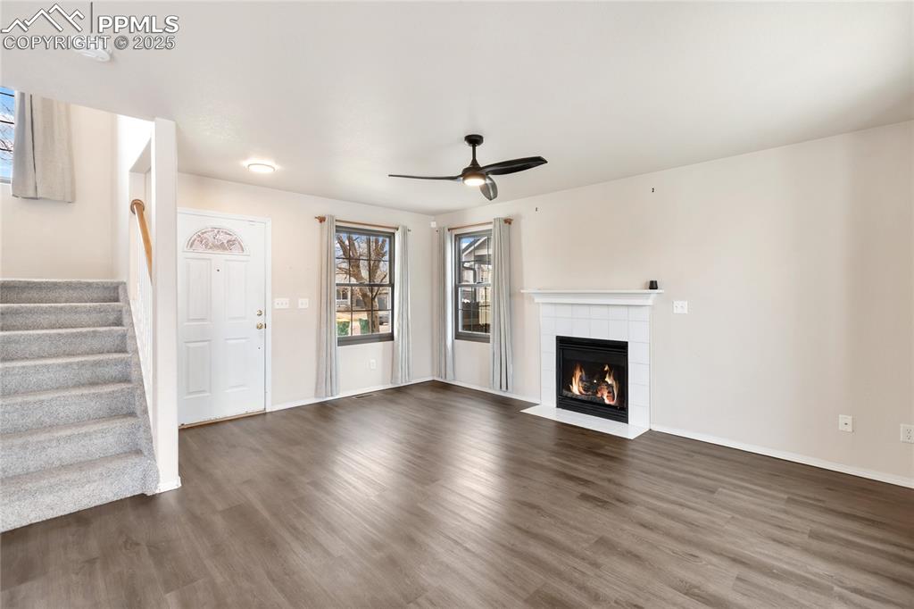 Image 6 of 37: Unfurnished living room featuring wood finished floors, ceiling fan, a tile