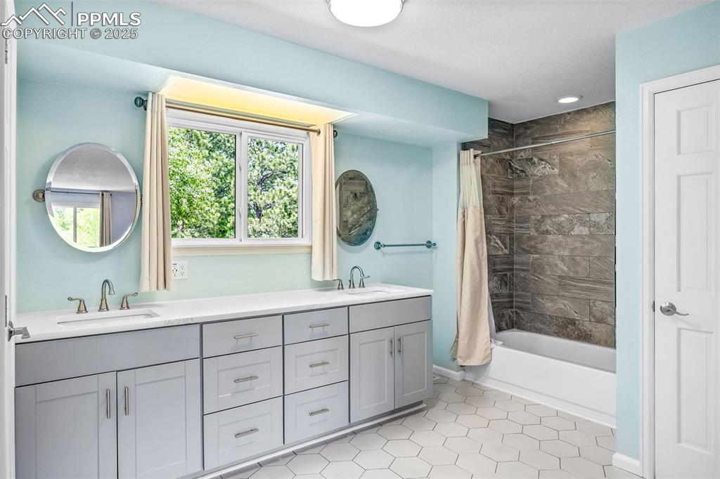 Image 15 of 47: Full bathroom featuring double vanity, shower / tub combo, tile patterned f