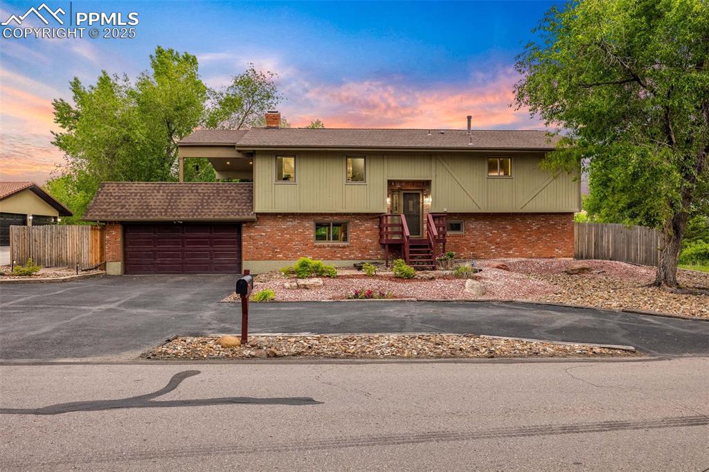 Image 2 of 47: Raised ranch featuring brick siding, a chimney, driveway, and an attached g