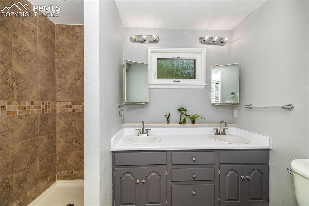 Image 23 of 47: Bathroom with double vanity and tiled shower