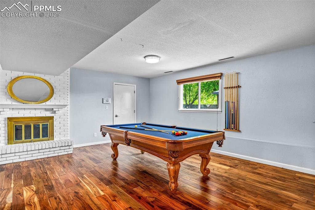 Image 25 of 47: Recreation room featuring a textured ceiling, wood finished floors, billiar