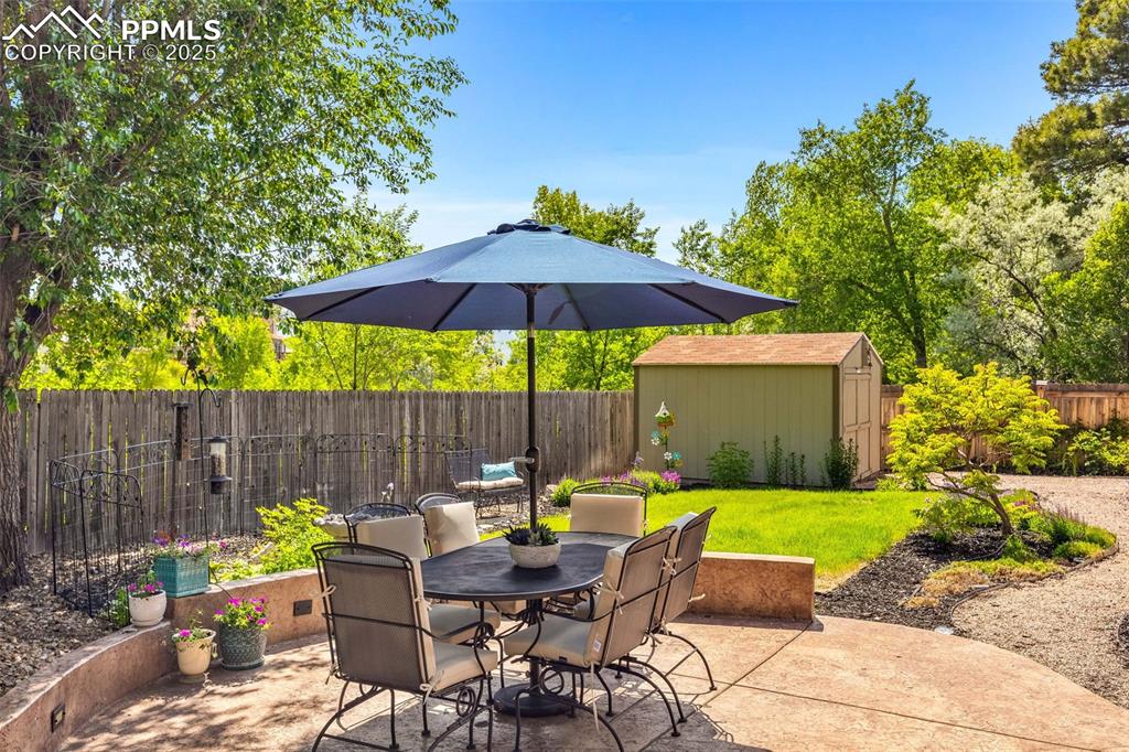 Image 31 of 47: Fenced backyard featuring a patio, a storage unit, and outdoor dining area