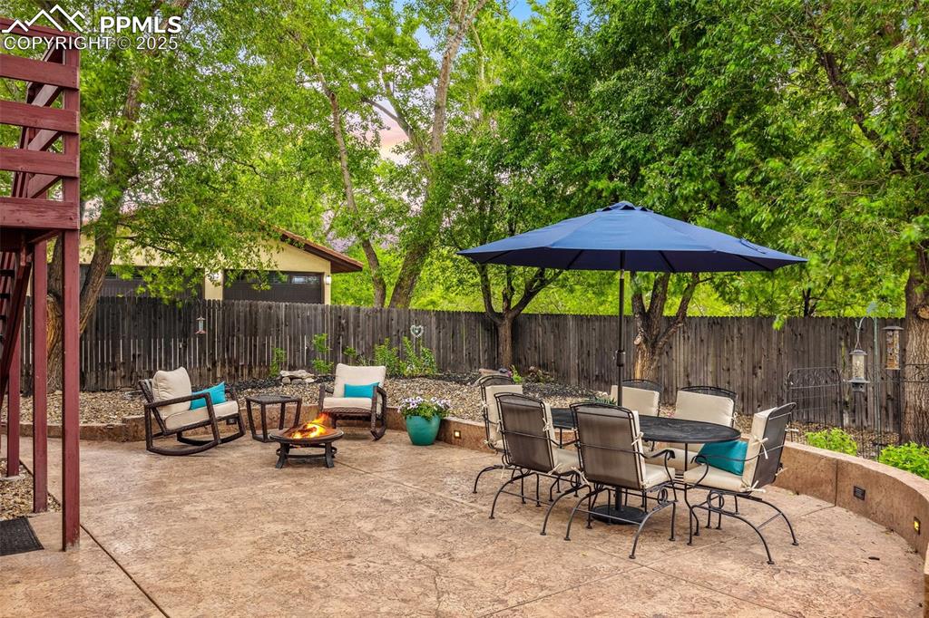 Image 41 of 47: Fenced backyard featuring a fire pit, a patio area, and outdoor dining area