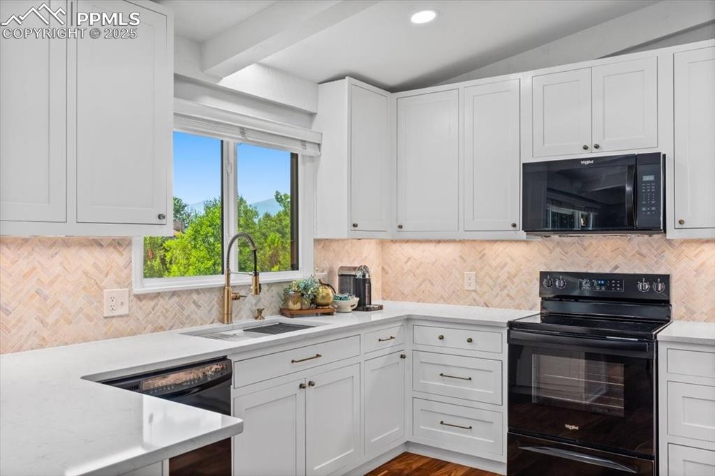 Image 6 of 47: Kitchen with black appliances, white cabinets, light stone countertops, dec