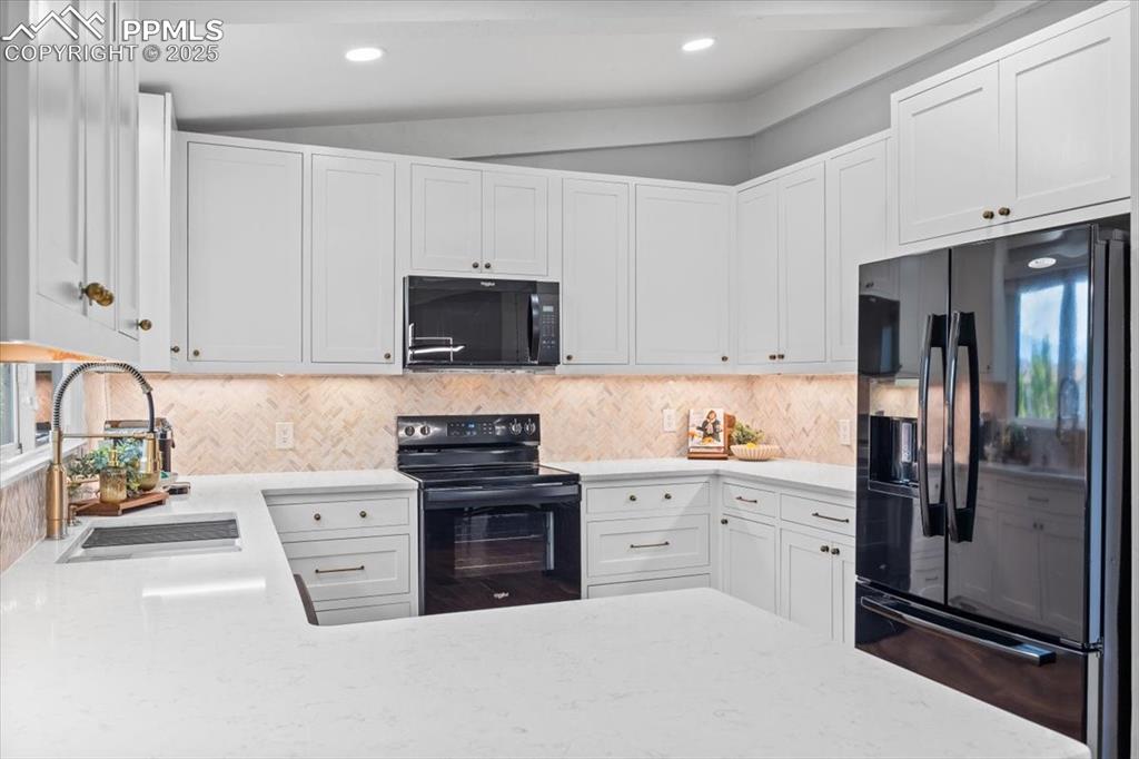 Image 8 of 47: Kitchen featuring black appliances, white cabinetry, decorative backsplash,
