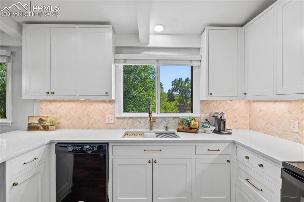 Image 9 of 47: Kitchen with black appliances, white cabinetry, decorative backsplash, and 