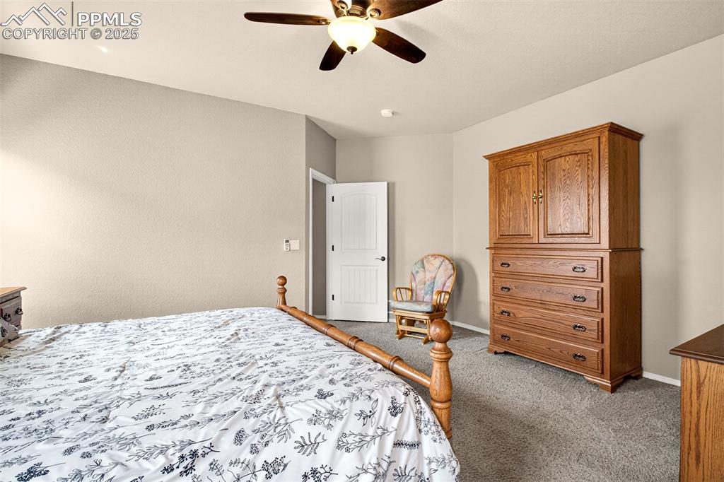 Image 23 of 48: Carpeted bedroom with a ceiling fan and baseboards