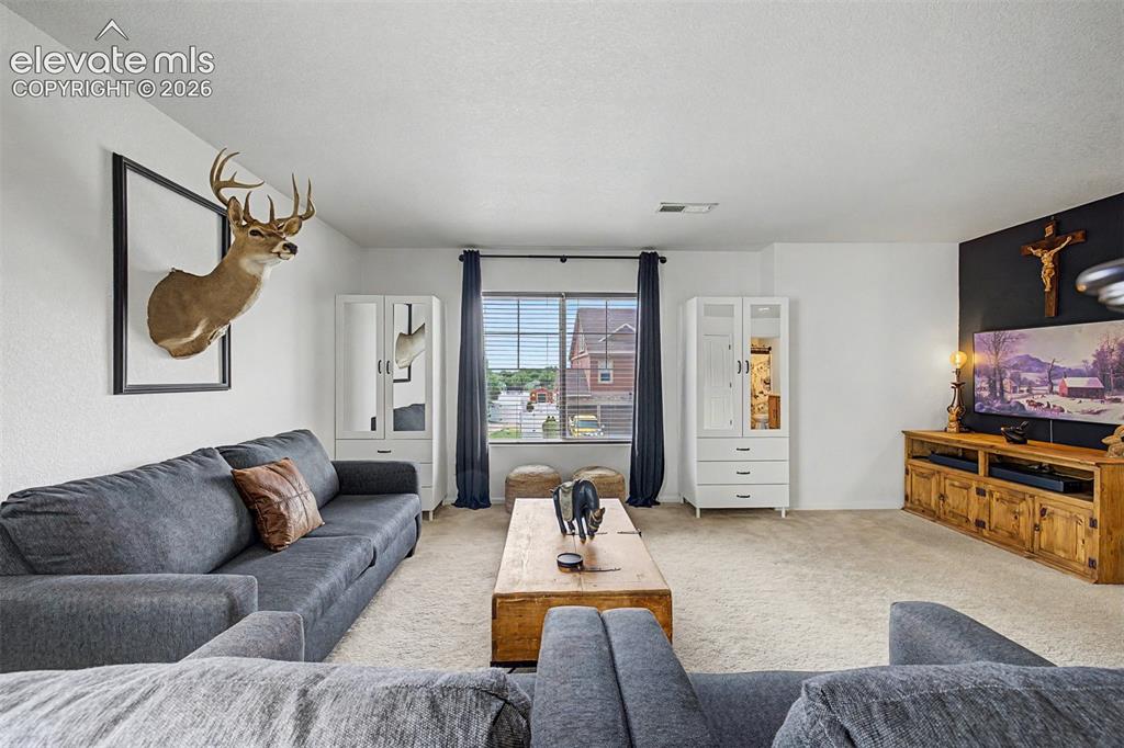 Image 19 of 43: The upstairs bonus room offers a relaxed retreat with plush sofas, a media