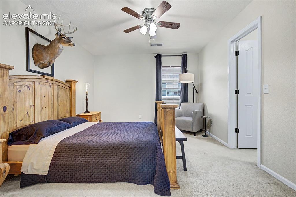 Image 32 of 43: A generously sized fourth bedroom with ceiling fan, large window, and plush